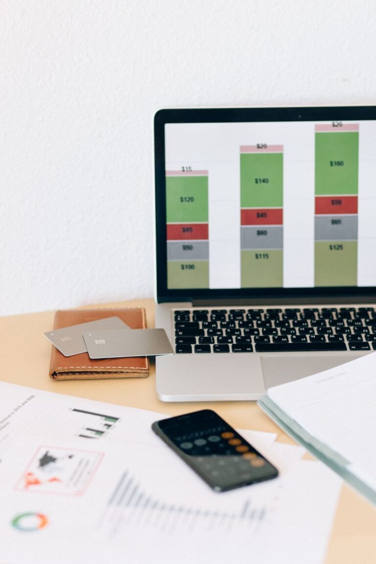 Laptop with a financial chart beside documents and cards